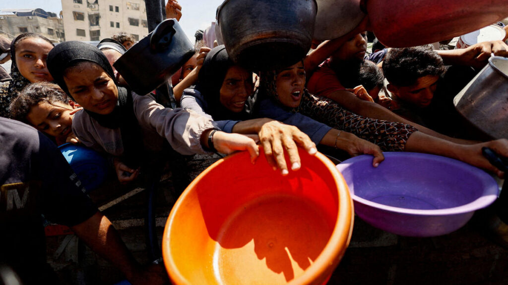FILE PHOTO: Palestinians wait to receive food from a charity kitchen, in Gaza City