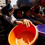 FILE PHOTO: Palestinians wait to receive food from a charity kitchen, in Gaza City