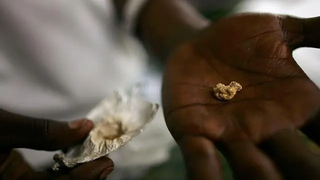 An individual holds a gold nugget in the palm of their hand